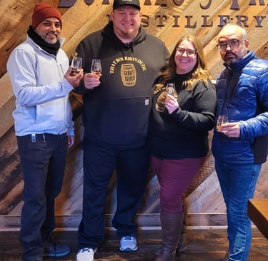 Four smiling people holding bourbon tasting glasses at the Buffalo Trace Distillery.