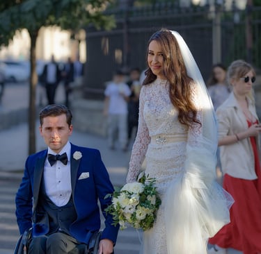 A man in a wheel chair on his wedding day with his bride.