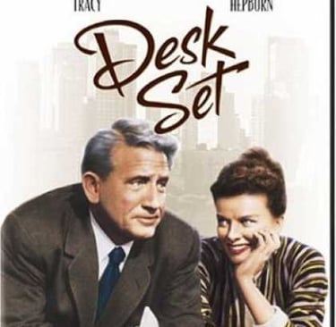 a man and woman sitting at a desk with desks