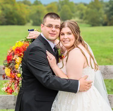 a bride and groom standing in front of a fenced in area