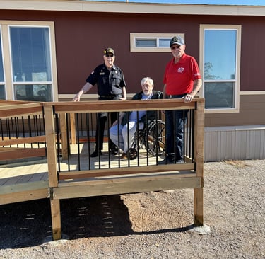 Image shows three gentlemen on a freshly constructed wheelchair ramp