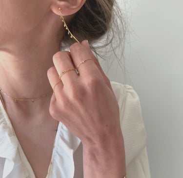 Photo bijoux BYNORA portés. Chaîne d'oreilles, bagues, sautoir et bracelet avec des diamants bruts multicolors