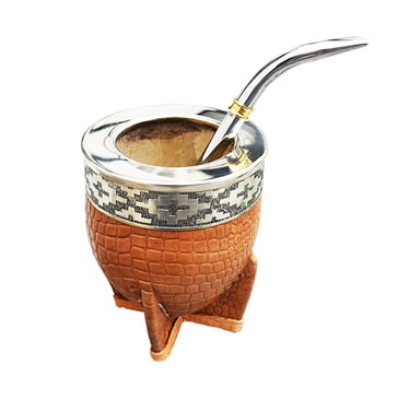 Handcrafted leather yerba mate gourd with silver rim and bombilla straw on a white background.