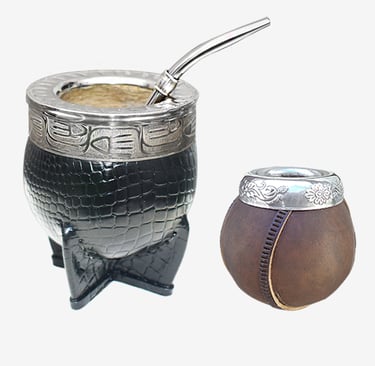 Two traditional yerba mate gourds featuring leather wrapping, ornate silver rims, and a metal bombilla straw.