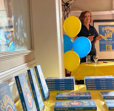 photo of a book launch with books on a table and balloons