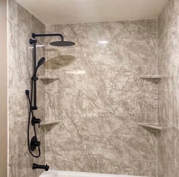 Elegant bathtub and shower combo featuring marble-look wall panels, matte black rainfall showerhead, and adjustable handheld
