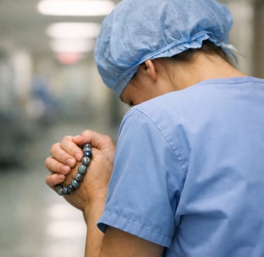 Soignante vue de dos dans un couloir d’hôpital, serrant un bracelet de labradorite.