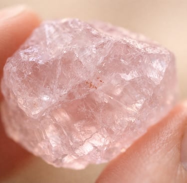 Gros plan d'un quartz rose brut tenu entre deux doigts
