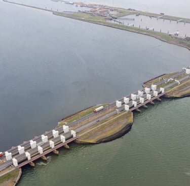 afsluitdijk - a train traveling over a bridge over a river