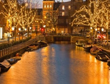 Amsterdam - a river with boats and christmas lights on it