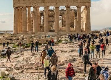 a group of people walking around a large stone structure