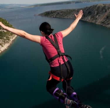 a woman in a pink shirt is standing on a ledge