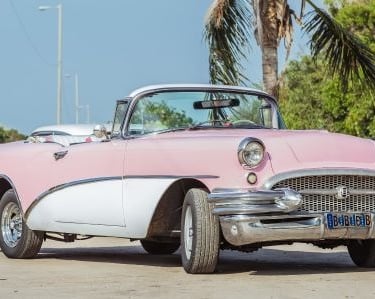 a classic pink car parked in a parking lot