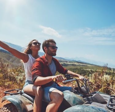 a man and woman riding on a quad - bike