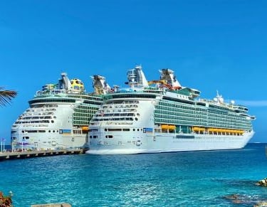 two cruise ships docked at a dock in the ocean