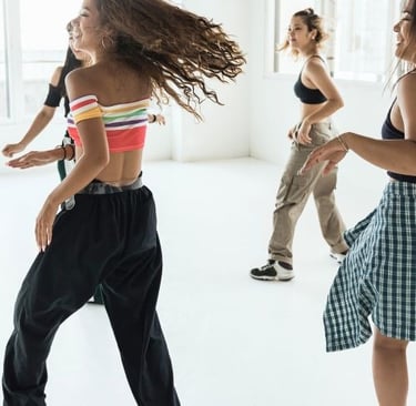 Diverse group of young women practicing hip hop dance moves in a bright, modern studio.