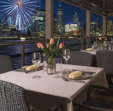 a table on a boat with plates and wine glasses, a ferris wheel in the background