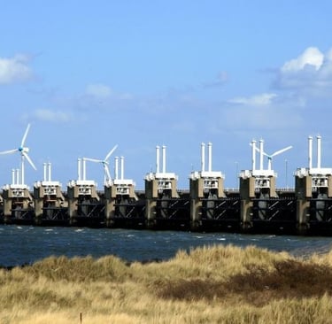 The Oosterscheldekering storm surge barrier in the Netherlands with wind turbines under a blue sky.