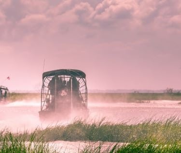 a airboat traveling through the water with a boat in the background