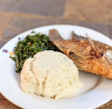 a fish fish on a plate with a side of mashed potatoes and greens