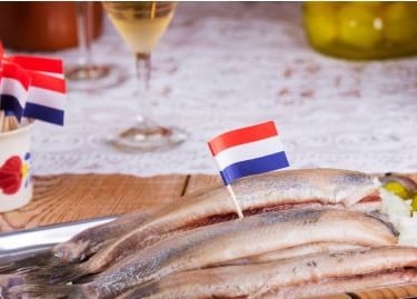 a tray of herring fish with a dutch flag on it