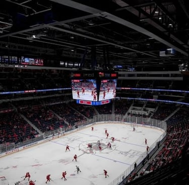 a hockey game in a stadium with a large screen