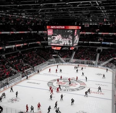 a hockey game in a stadium with a large screen