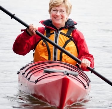 a woman in a red jacket is kayaking in a kayak