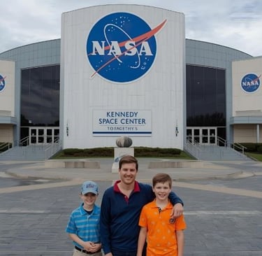 a man and two children standing in front of a nasa shuttle