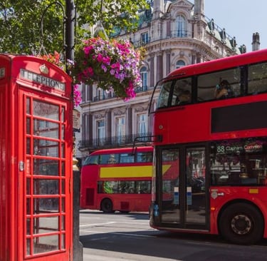 a red double decker busses parked next to a red phone booth