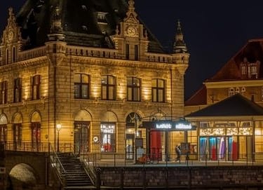 a luxury historical hotel building with a clock tower and a bridge over water
