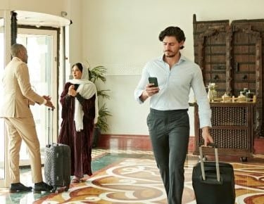 a man in a suit case walking through a hotel lobby