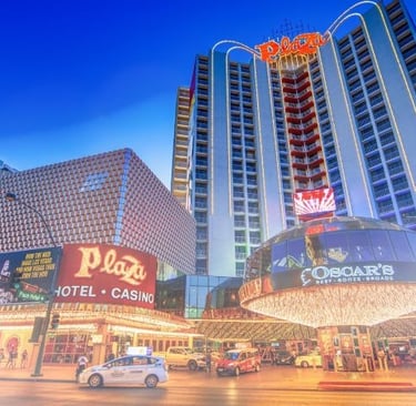 Exterior of the Plaza Hotel and Casino in downtown Las Vegas at dusk with neon lights and Oscar's steakhouse.