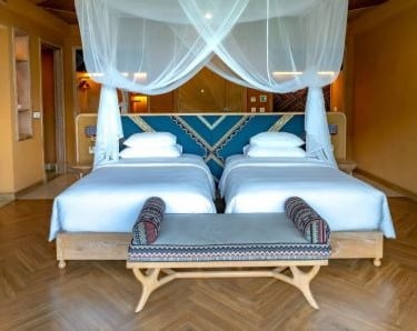 a hotel bedroom with two beds and a bench