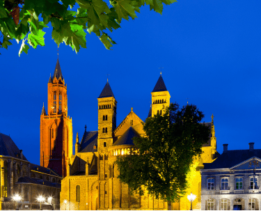 Illuminated Basilica of Saint Servatius and Saint John's Church at night in Maastricht.