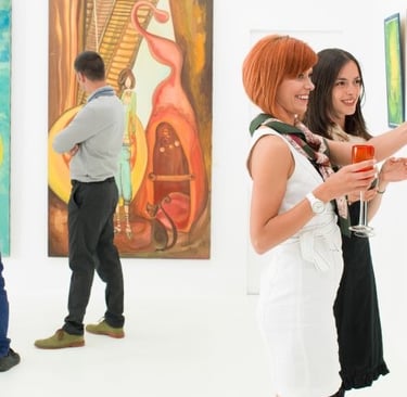 Smiling people viewing abstract paintings at a modern art gallery exhibition.