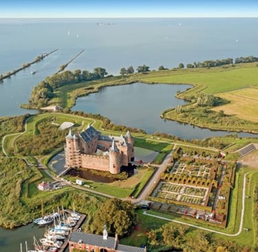 Aerial view of Muiderslot Castle with historic gardens, moat, and boats on the water in Muiden.