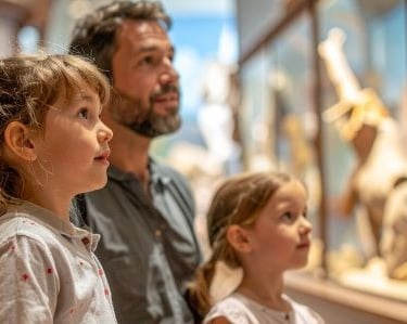 a man and a little girl are looking at a display of a museum