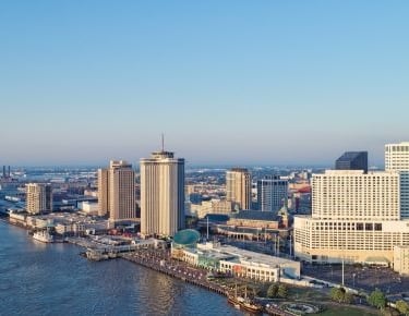 new orleans city skyline with a river and a bridge