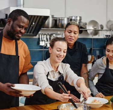 a group of people standing around a table with plates of food
