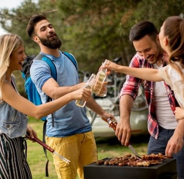 a group of people standing around a grill/bbq
