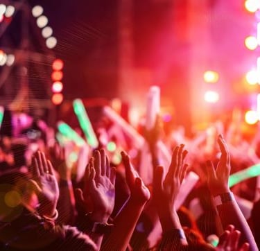 a crowd of people standing in front of a stage with bright lights