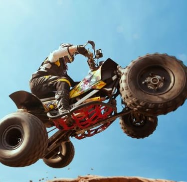 Quad Bike - a person riding a dirt bike on a dirt track