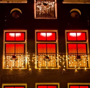 Traditional Dutch building facade at night decorated with glowing Christmas lights and festive ornaments.