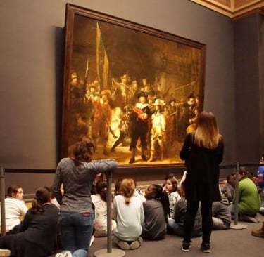 rembrandt painting - a group of people sitting on the ground in a museum
