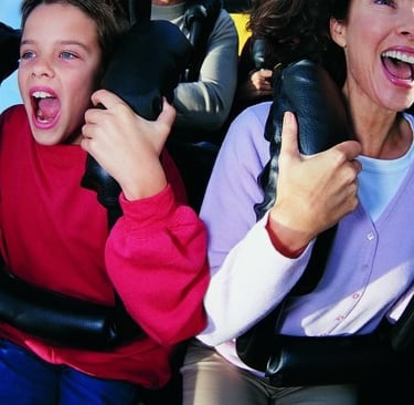 a woman and a boy are riding on a roller coaster