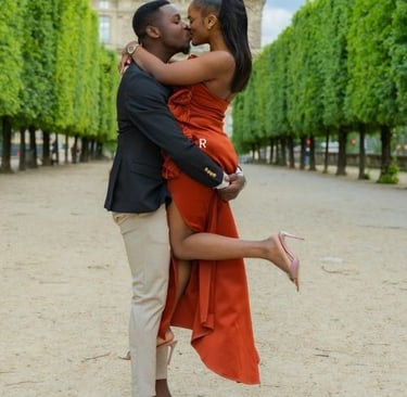a man and woman kissing in front of a tower