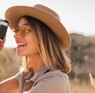 a woman in a hat and sunglasses is taking a picture of wildlife