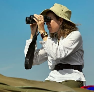 a woman looking through binoculars for wildlife on a safari