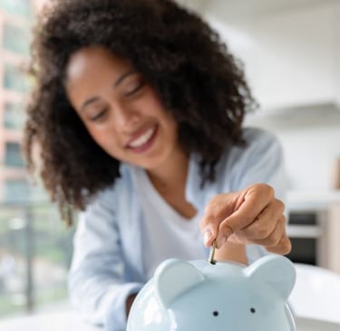 a woman putting coins into a piggy bank
